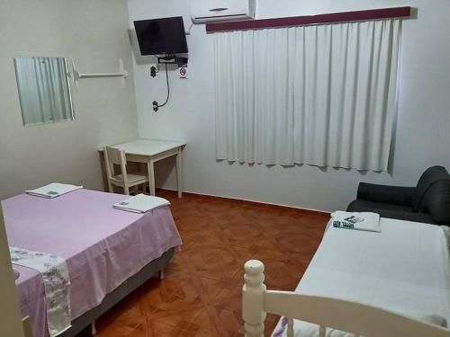 a room with a bed and a table and a tv at Hotel Avenida - Hotel do Morais - Salto do Lontra in Salto do Lontra