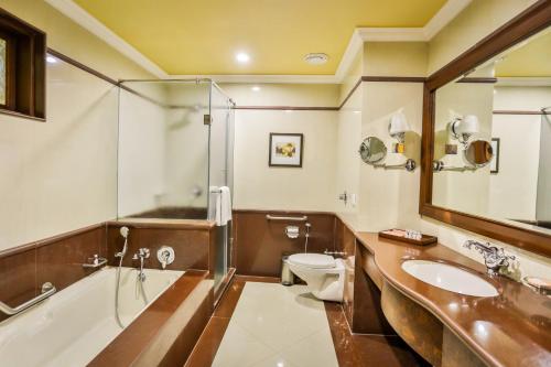 a bathroom with a tub and a sink and a toilet at Regency Lagoon Resort in Rajkot