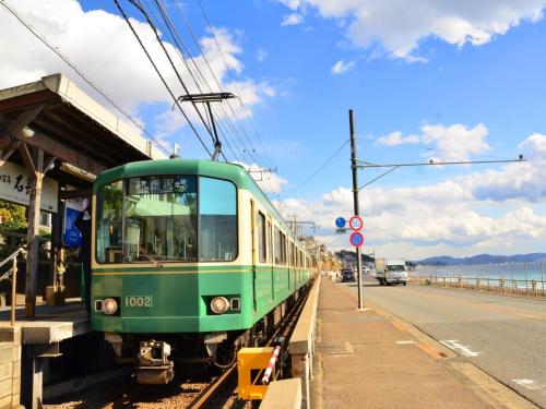 a green train is parked at a train station at Kamakura COCON in Kamakura