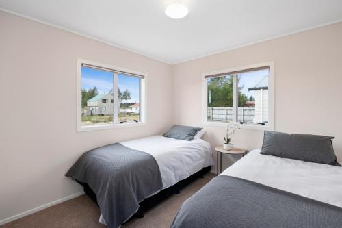 two beds in a white room with two windows at Fifteen B - National Park Holiday Home in National Park