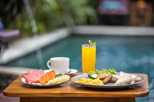a table with two plates of food and a drink at Uma Sari Cottage by Mahaputra in Ubud