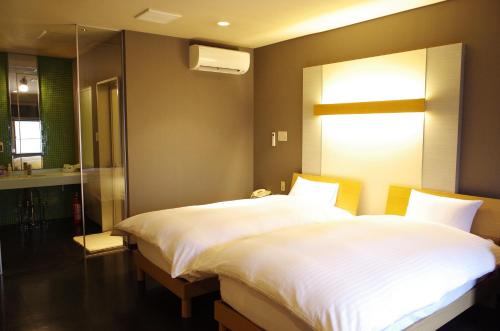 a bedroom with a large white bed and a bathroom at Bar 39 in Higashihiroshima