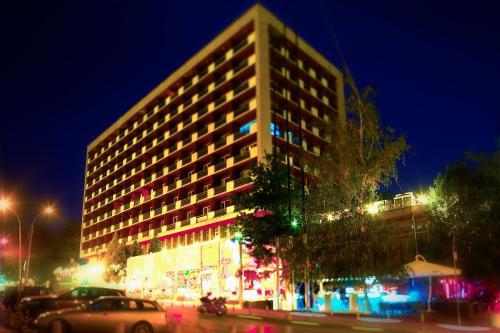 a tall building at night with cars parked in front of it at Rila Hotel Sofia in Sofia