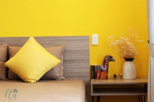 a bedroom with a bed with a yellow wall at Na Homestay in Hue