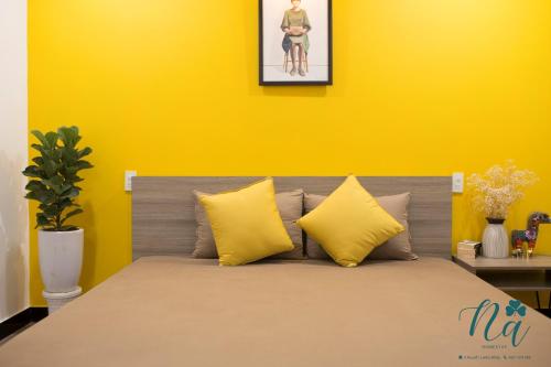 a bedroom with yellow walls and a bed with yellow pillows at Na Homestay in Hue
