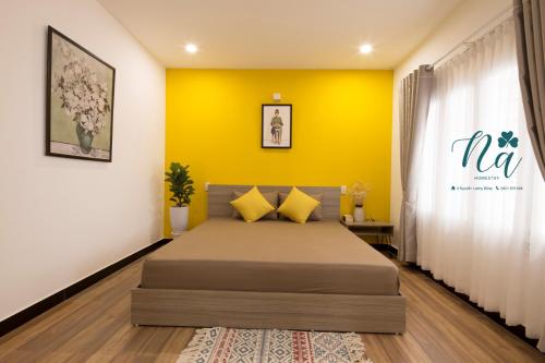 a bedroom with a bed and a yellow wall at Na Homestay in Hue