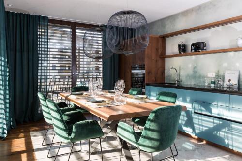 une salle à manger avec une table en bois et des chaises vertes dans l'établissement ANTON Dolomites Hideaway, à Brunico