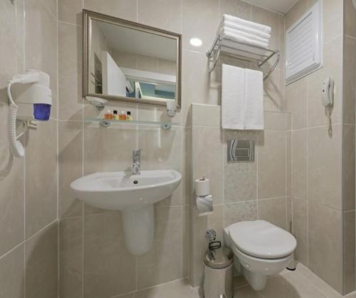 ein Badezimmer mit einem Waschbecken, einem WC und einem Spiegel in der Unterkunft Kleopatra Life Hotel in Alanya