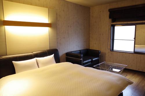 a bedroom with a bed and a leather chair at Bar 39 in Higashihiroshima