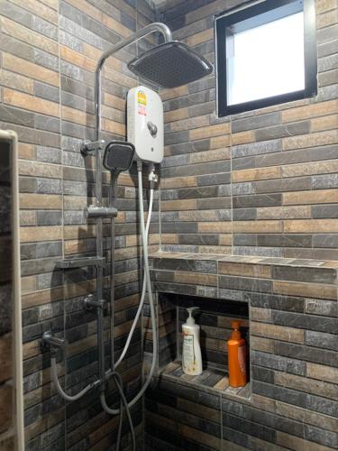 y baño con ducha y TV en una pared de ladrillo. en Youniverse Homestay, en Chiang Mai