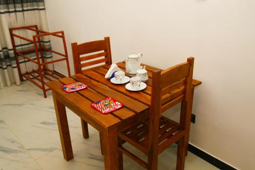 a wooden table and chairs with a tea set on it at Verona D' Oro in Dickwella