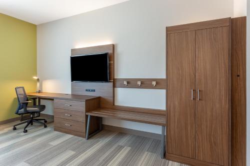 a wooden desk with a television on top of it at Holiday Inn Express & Suites - Springfield North, an IHG Hotel in Springfield