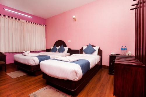 two beds in a room with pink walls and wooden floors at Hotel Green Horizon in Kathmandu