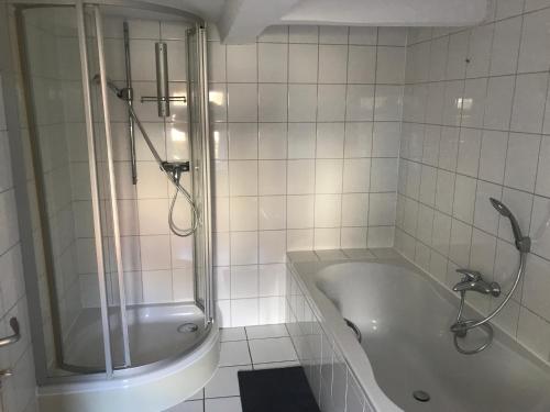ein weißes Bad mit einer Badewanne und einer Dusche in der Unterkunft Drei Linden Harz in Wolfenbüttel