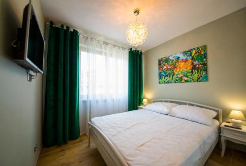 a bedroom with a large bed with green curtains at Wyspa Uznam - Rondo Róży Wiatrów in Świnoujście