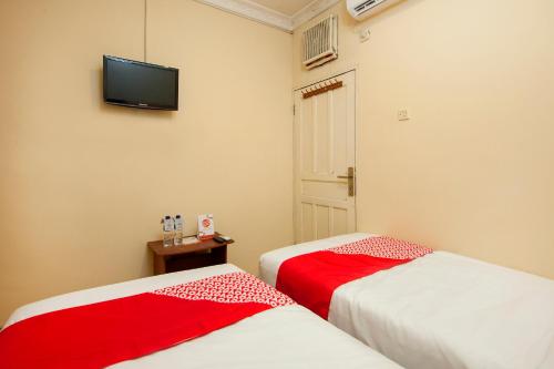 two beds in a room with a tv on the wall at OYO 2045 Hotel 211 in Parapat