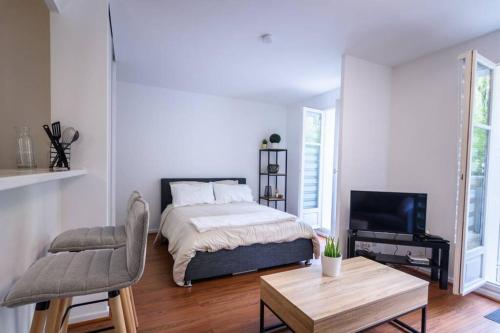ein Schlafzimmer mit einem Bett, einem Fernseher und einem Tisch in der Unterkunft TOP Cosy studio avec Terrasse à 10min Disney-Shopping Vallée in Bailly-Romainvilliers