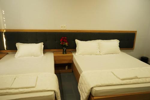 two beds in a room with a vase of flowers at Tina 2 Hotel in Cái Răng