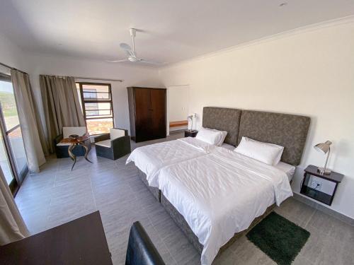 sypialnia z dużym białym łóżkiem z białą pościelą w obiekcie Otjohotozu Guestfarm w mieście Omaruru