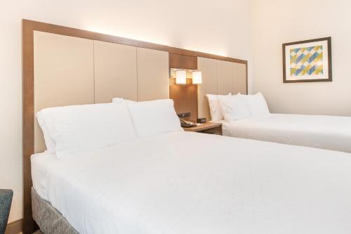 two beds in a hotel room with white sheets at Holiday Inn Express & Suites Columbia-I-26 @ Harbison Blvd by IHG in Columbia