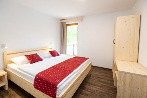 a bedroom with a bed with red pillows and a window at Bohinj Apartments Goldhorn Kingdom in Bohinj