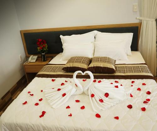 a bed with two white wedding towels with hearts at Tina 2 Hotel in Cái Răng