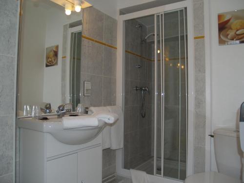 a bathroom with a sink and a glass shower at Hôtel Central in Pau