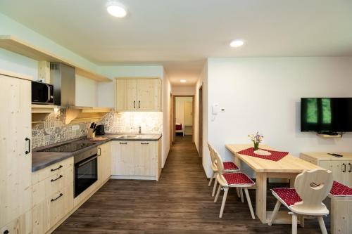 a kitchen with white cabinets and a table and chairs at Bohinj Apartments Goldhorn Kingdom in Bohinj
