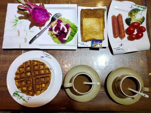 a table with a plate of waffle and two cups of coffee at Pingyao HongJingYuanGuesthouse in Pingyao