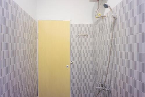 a bathroom with a shower with a yellow door at OYO 1811 Citra Anggrek in Medan