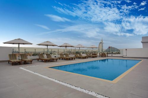 a swimming pool with chairs and umbrellas on a roof at Lemon Tree Hotel, Jumeirah Dubai in Dubai