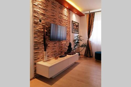 a living room with a tv on a brick wall at Oasis felix apartment in Belgrade