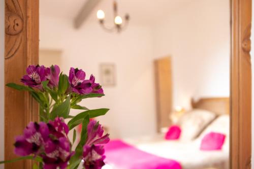 a vase with purple flowers in front of a bedroom at Mas des Tourterelles in Saint-Rémy-de-Provence