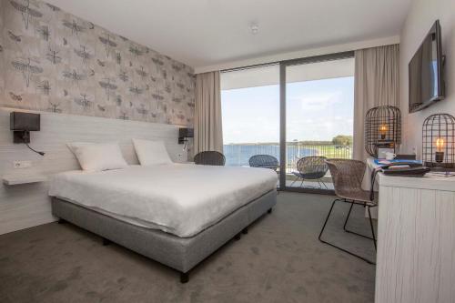 アルネマイデンにあるFletcher Hotel-Restaurant Het Veerse Meerのベッドとバルコニー付きのホテルルーム