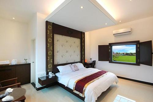a bedroom with a large bed and a large window at Lo Hong ka Countryside House in Luodong