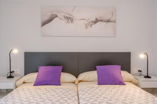 1 dormitorio con 1 cama con almohadas moradas en Congresos Granada Apartment by A3Rentals, en Granada