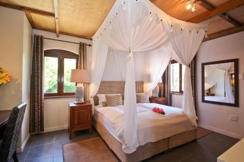 Schlafzimmer mit Himmelbett und weißen Vorhängen in der Unterkunft Montrose Guesthouse in Somerset West