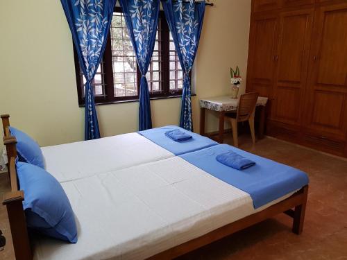 um quarto com uma cama com cortinas azuis e uma janela em Birds Nest Home Stay em Cochin