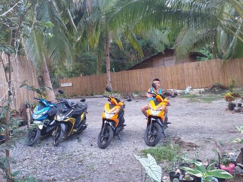a man sitting on three motorcycles parked next to a fence at GREENSPACE in Panglao