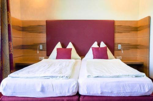 2 camas en una habitación de hotel con almohadas rojas y blancas en Fischwirtshaus Landmotel Die Donaurast, en Persenbeug