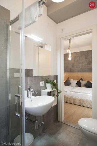 a bathroom with a sink and a bedroom with a bed at Sleep In Udine in Udine