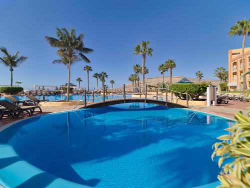 a swimming pool with a bridge and palm trees at H10 Playa Esmeralda - Adults Only in Costa Calma