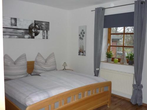 una camera da letto con un letto con cuscini bianchi e una finestra di Ferienwohnung im Wiesengrund a Tarp