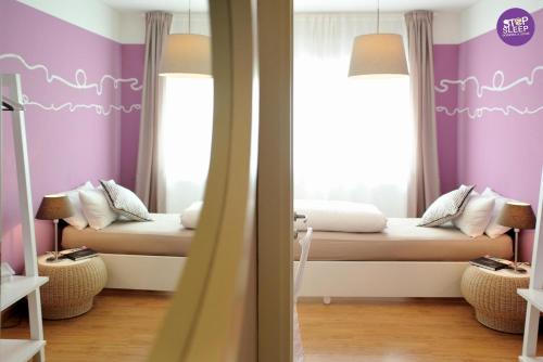 a bedroom with two beds with purple walls and a mirror at Stop & Sleep Udine in Udine