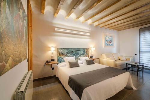 Un dormitorio con una cama grande y una silla. en Hotel Boutique Arte y Descanso, en Almagro