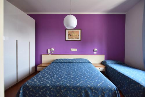 1 dormitorio con paredes moradas y 1 cama azul en Hotel Azzurra, en Rímini