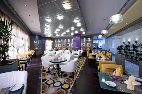 a restaurant with white chairs and tables and tablesktop at TIME Grand Plaza Hotel, Dubai Airport in Dubai