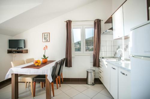 a small white kitchen with a table and a window at Kaja - right next to the beach in Trogir