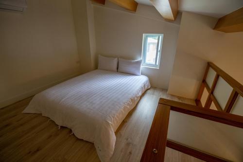 a small bedroom with a white bed with a window at Songhe ShanShuei B&B in Heping