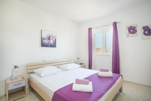 a bedroom with a bed and a window with purple curtains at Kaja - right next to the beach in Trogir